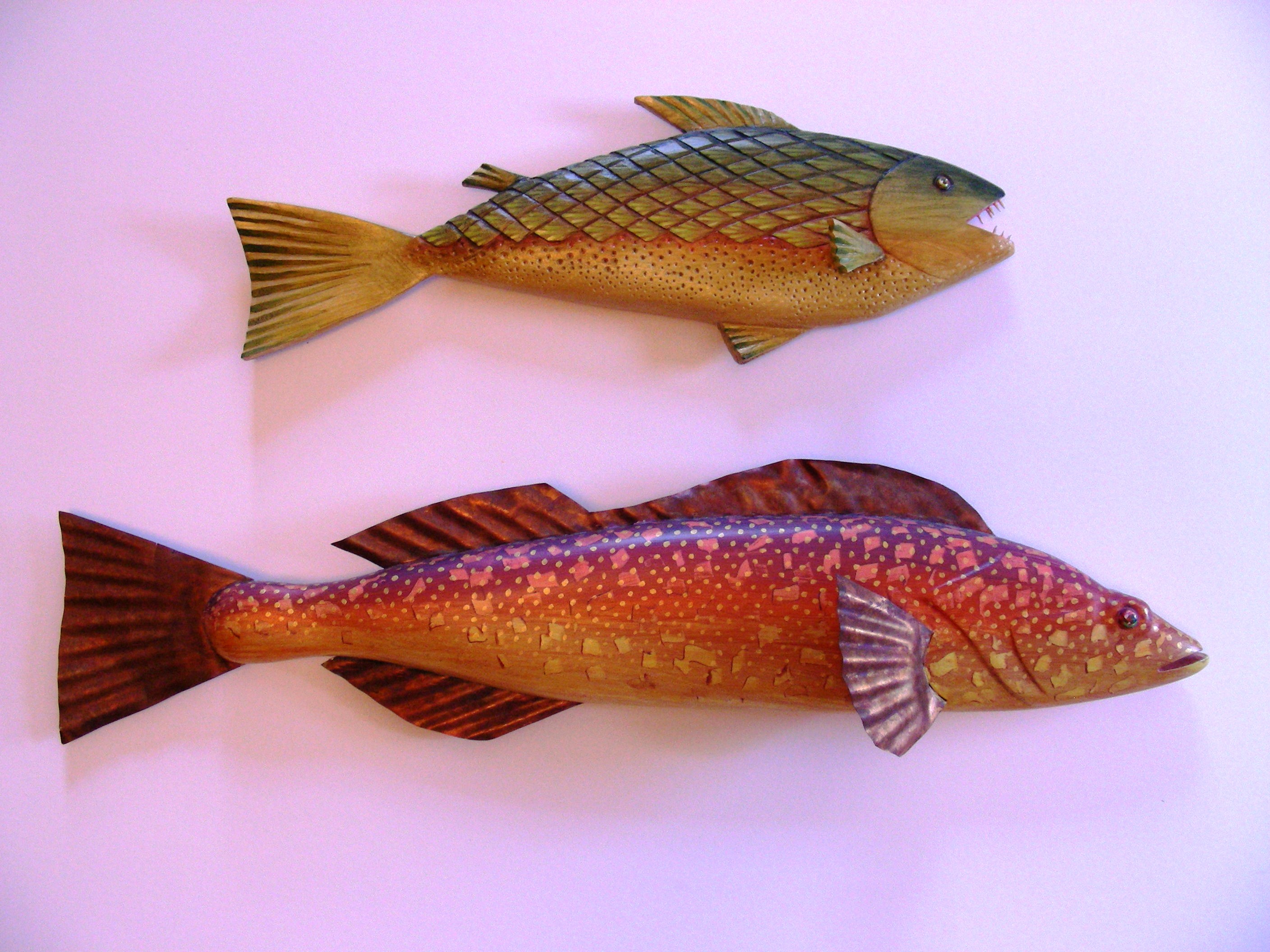 image of two fish, each carved of wood and painted, with copper teeth and copper fins